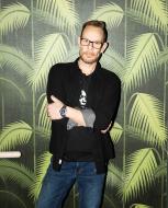 DJ Rob Faust standing against palm tree pattern wall paper