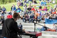 Outdoor setting with a musician on stage in front of a crowd