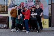 Midnight channel collective standing against a graffitied wall. 