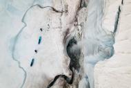 Two people pulling kayaks on a glacier 